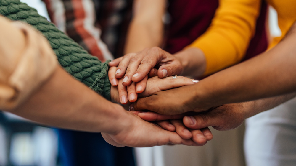 Group of all aged people, holding hands together, one over the other.